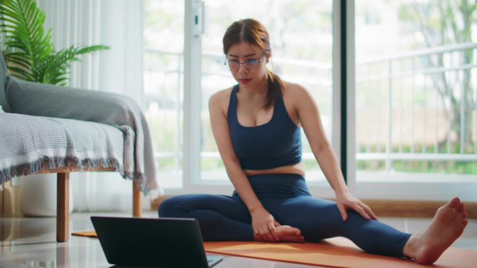 健康女性通过笔记本电脑、网络课程、远程健身房进行锻炼