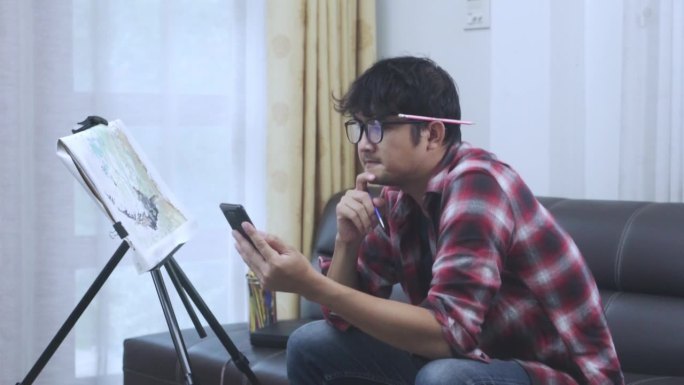 亚洲年轻人以手机图片为范本，在家中创作油画彩水。