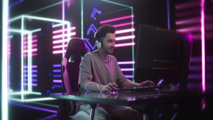年轻英俊的玩家在电脑上玩在线视频游戏。一个戴着耳机的兴奋男人的肖像在PvP锦标赛中与其他玩家战斗，通