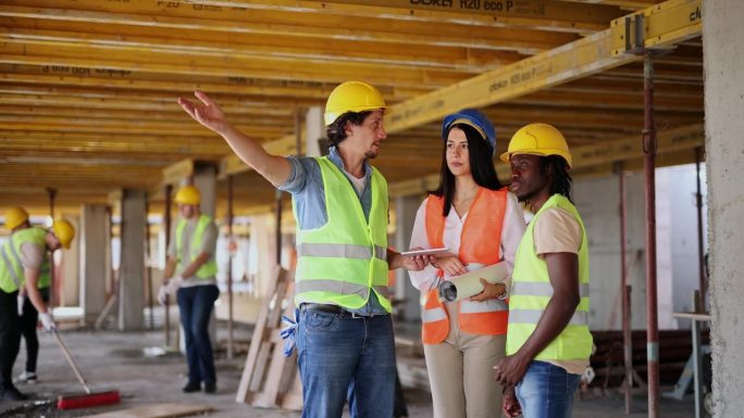 女工程师在建筑工地向建筑工人展示平板上的蓝图