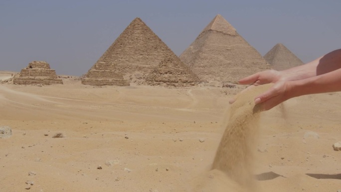 女性的手是带着沙子和埃及吉萨大金字塔的。