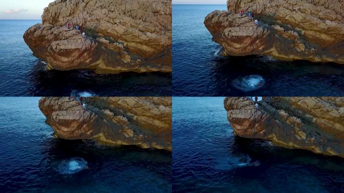 孩子从岩石上跳入水中的空中圆形镜头