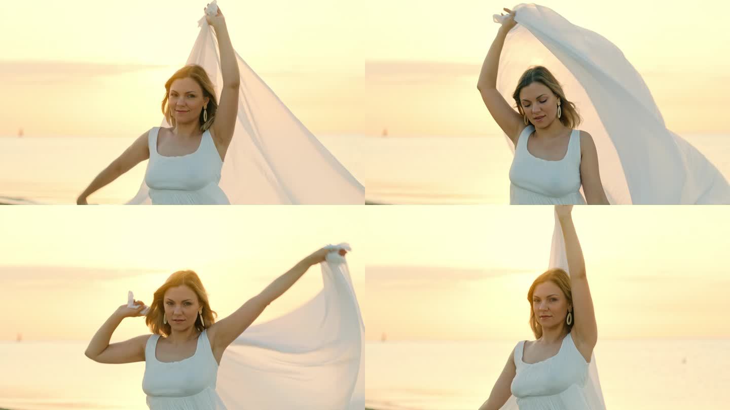 美丽的女人站在海边，拿着白色的长披肩，像风帆在风中飘扬。女性的概念，温柔，自由。