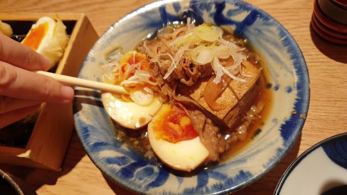 用手筷子吃小配菜的日本居酒屋料理豆腐炖牛肉和鸡蛋菜4k