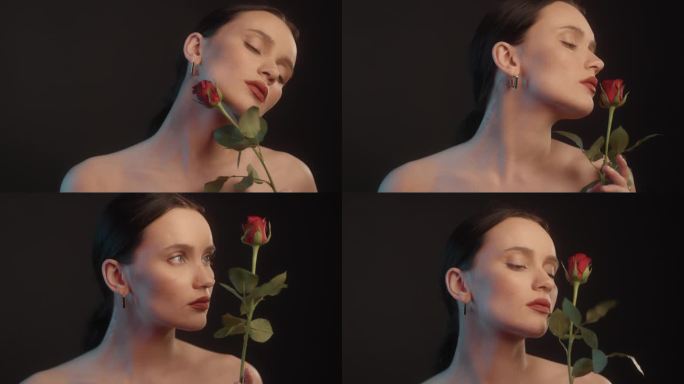 美丽感性的女人与红色的口红黑色背景工作室拍摄的姿势，看着单一的红玫瑰