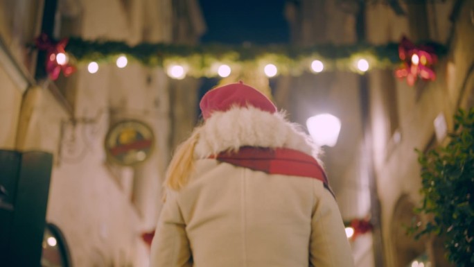 一名女子悠闲地走在萨尔茨堡一条充满活力的圣诞主题小巷里