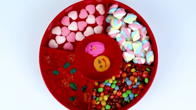 一套不同的美味的糖果在一个红色的糖果盒孤立的白色背景