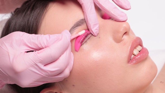 在美容院，化妆师正在为一位美女进行睫毛的分层和染色。睫毛扩展。睫毛特写