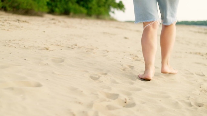 女人赤脚在沙滩上奔跑。一位年轻女子的脚踩在沙滩上。沙滩上赤脚的女孩。暑假