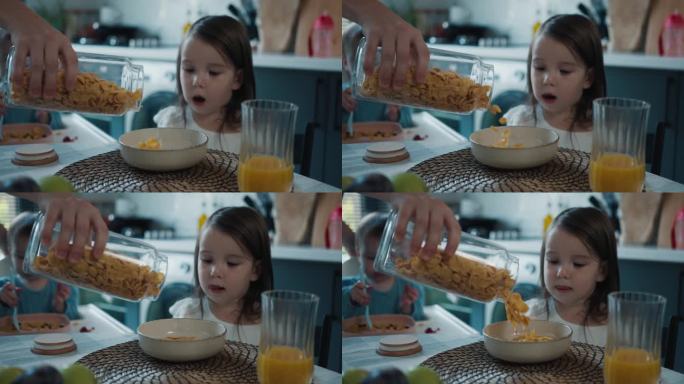妈妈把早餐用的玉米片倒进小女儿的碗里