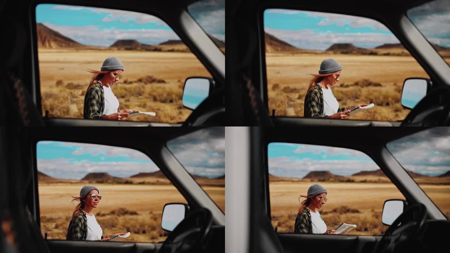 一个女人看着她停在沙漠某处的露营车旁边的地图