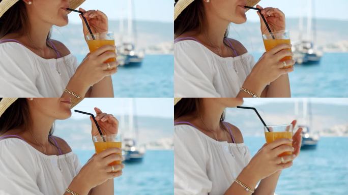 在码头上的一家海滨咖啡馆凉亭里，一位黑发女子正在享用她的橙汁。夏日的精华，假日的幸福，放松，和旅游的