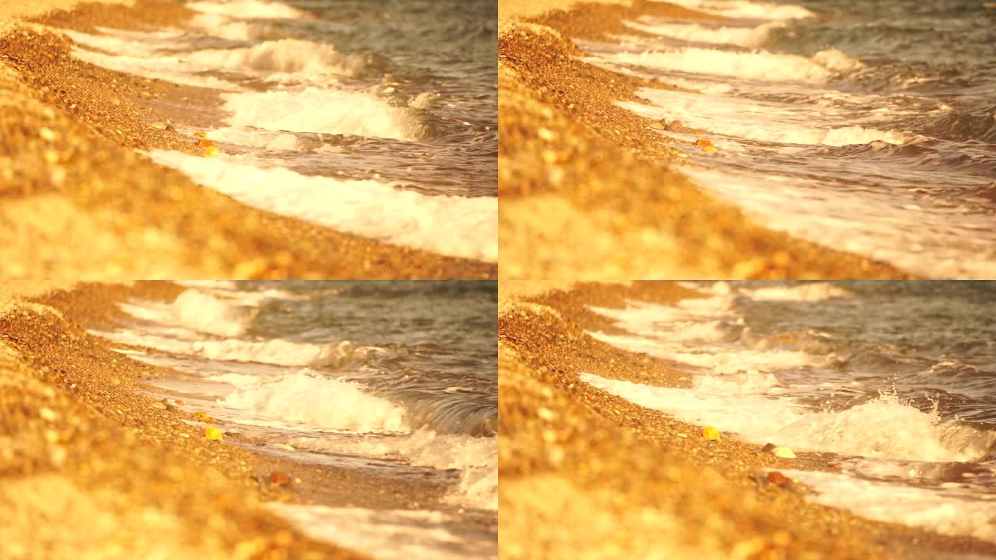 小海浪，模糊的软泡沫海浪冲刷金色卵石沙滩夕阳。海滩上的海浪。没有人。假日休闲概念。抽象航海夏季海洋日