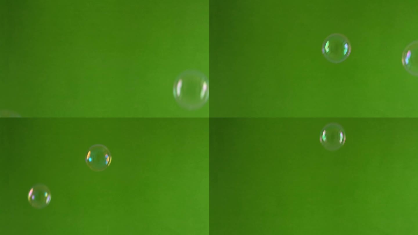 绿色背景上许多快速下落的彩虹肥皂泡。