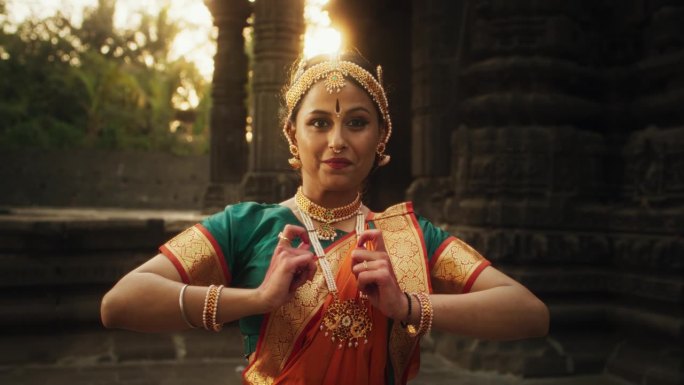 富有表现力的年轻印度女孩的肖像，穿着五颜六色的传统纱丽，在一座古老的寺庙里表演了一场戏剧性的婆罗塔那