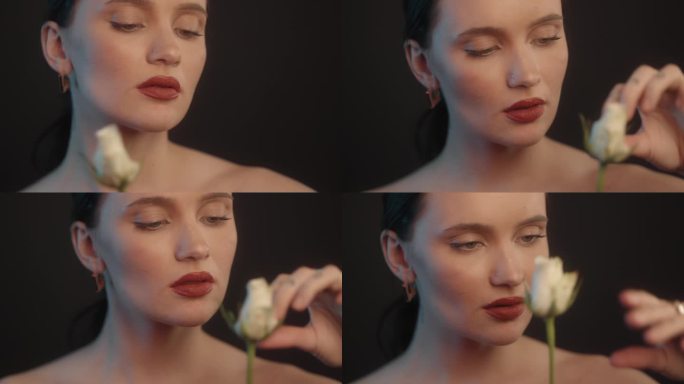 爱我的，不爱我的。性感的女人用红色的口红在摄影棚拍摄，她拿着一朵白玫瑰，正在采摘花瓣