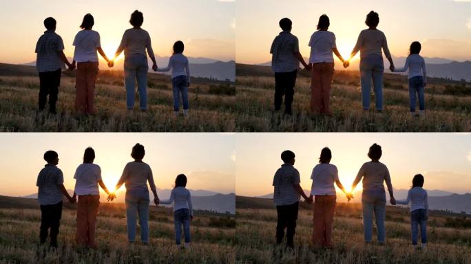 妈妈和三个孩子手牵着手站在农村的田野里，看着夕阳的背影。夕阳西下，一家人手拉手走过割过的麦田。友好家