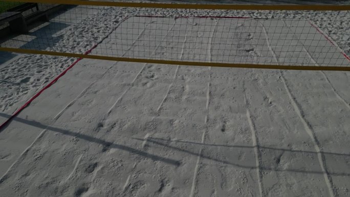 白色的沙滩排球场。白色柔软的沙丘用网围起来。运动场的线条是由蓝色纺织塑料带制成的