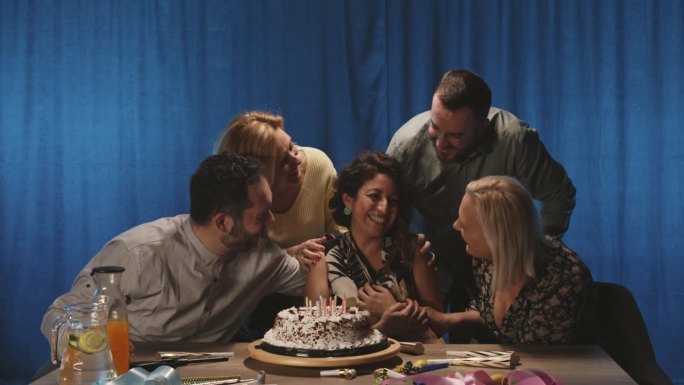 一群人在蛋糕上吹蜡烛，祝他们的朋友生日快乐