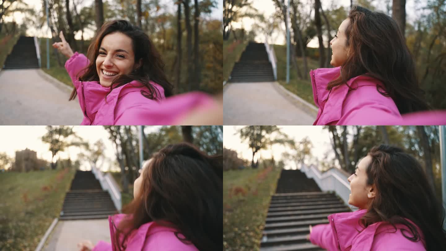 快乐的漂亮女人一边用手机自拍，一边享受在公园里散步。时令风格，秋高气爽。积极情绪的概念。慢动作