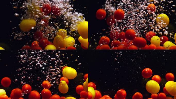 红色和黄色的圣女果落在透明的水中，黑色的背景。各种新鲜成熟的有机蔬菜在水族箱中飞溅，产生气泡。