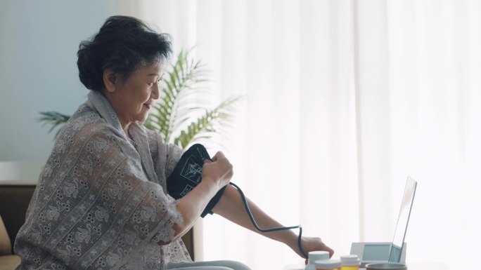 开朗的奶奶在客厅用电脑和医生交谈。她自己测量血压和心率，并询问药物。
