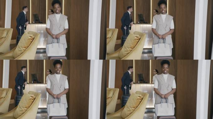 非裔美国商务女性的肖像，提着行李站在酒店大堂