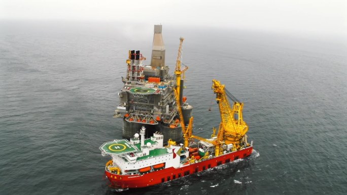 海上石油平台的俯视图，旁边有一艘支持船。