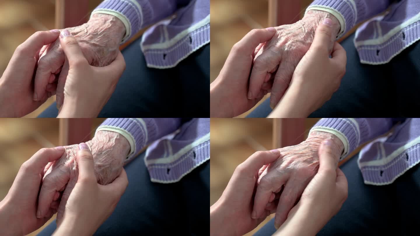 特写老年妇女的手与她的照顾者帮助的手握在一起，照顾者访问家中。家庭保健和养老院的概念。高品质4k画面