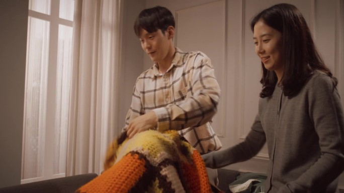 幸福的韩国家庭在家里共度美好时光:年轻的父母用毯子为他们可爱的孩子建造堡垒。孩子们开玩笑玩，享受童年