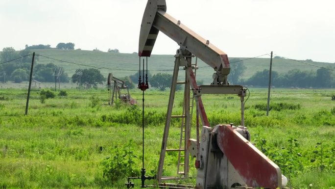 美国农村地区原油化石燃料的油井钻探。美国石油工业主题。泵移动的航拍视差长镜头。