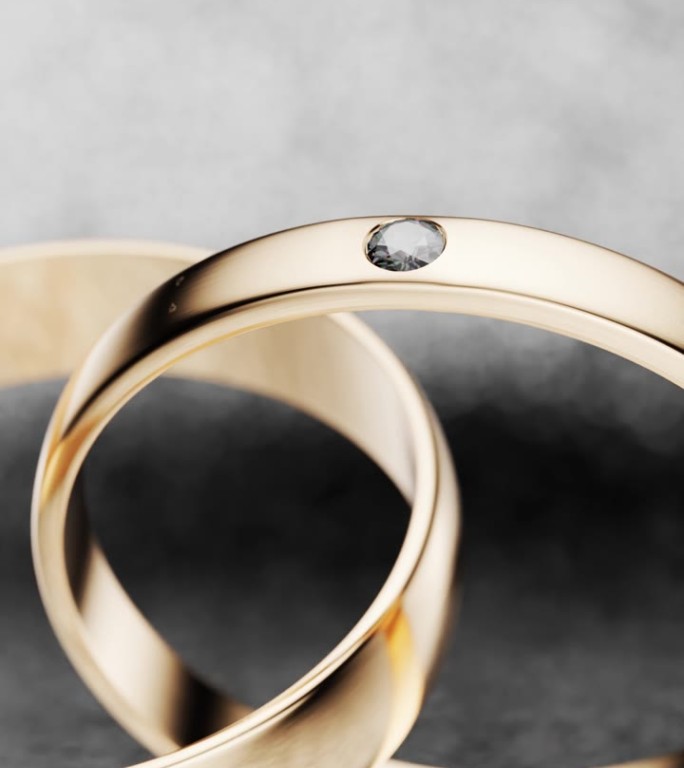 这对新婚夫妇的金婚戒在闪亮的背景上的特写。把相机绕着两个金环旋转。3 d渲染。