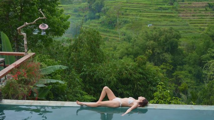 一名女子在巴厘岛别墅的泳池边放松