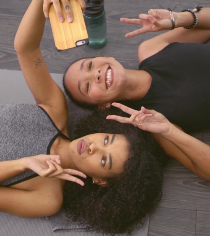 瑜伽，女性朋友和在地板上自拍，健身房和顶景和平标志，社交媒体和健康。非洲健身影响者，图标或亲吻头像，