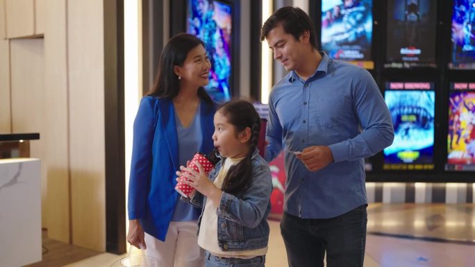 快乐的亚洲家庭准备一起去电影院看电影。欢快的亚洲家庭拿着碳酸饮料和爆米花去电影院看电影。家庭活动