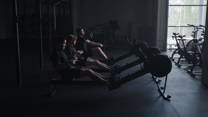 高强度有氧运动，三个年轻人在健身俱乐部的健身机上训练