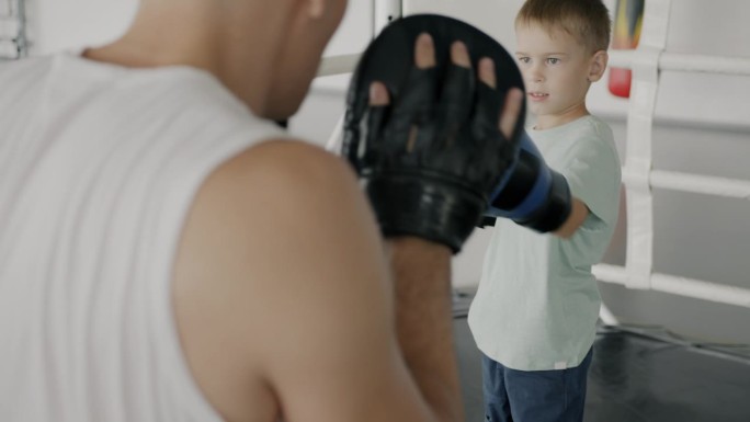 积极的孩子训练教练的拳击戴上手套集中在拳在健身房