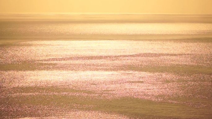 抽象空中大海夏天海洋日落自然背景。平静水面上的小波浪在运动中与太阳的金色散景灯模糊。度假、度假、休闲