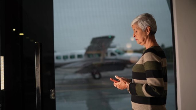 一位老妇人在机场贵宾休息室用完手机后沉思