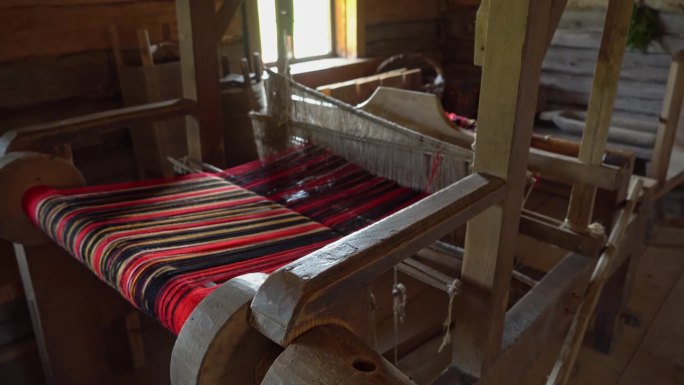 一间旧茅屋里的古老织布机，一台针织纺纱机。一个生产腰带、毛巾和衣服的老工厂