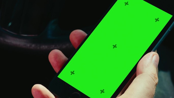 一名男子在车内用绿屏色度键解锁手机的特写镜头。垂直方向。