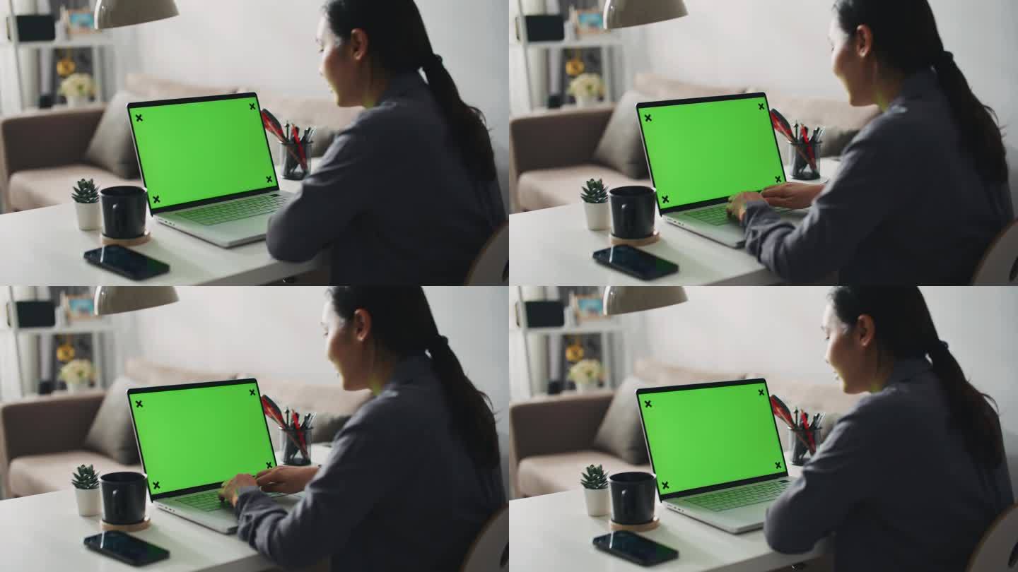 妇女在家里使用绿屏笔记本电脑