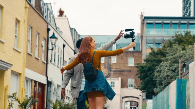 年轻夫妇一起旅行通过城市视频记录到手持三脚架摄像机