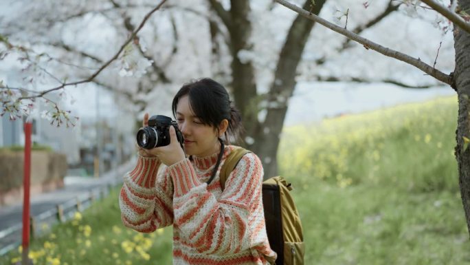 亚洲女性旅行者在假期用相机拍摄樱花