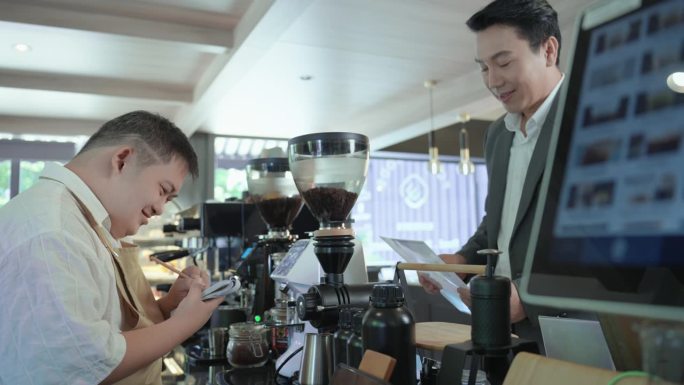 年轻的亚洲残疾男子早上在咖啡店接到穿着西装的英俊顾客的订单，要求他制作特别的热咖啡。咖啡厅雇佣残障人