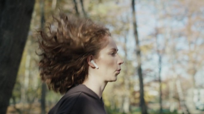 秋天在公园慢跑的白种姜色女人。用RED氦相机在8K下拍摄。