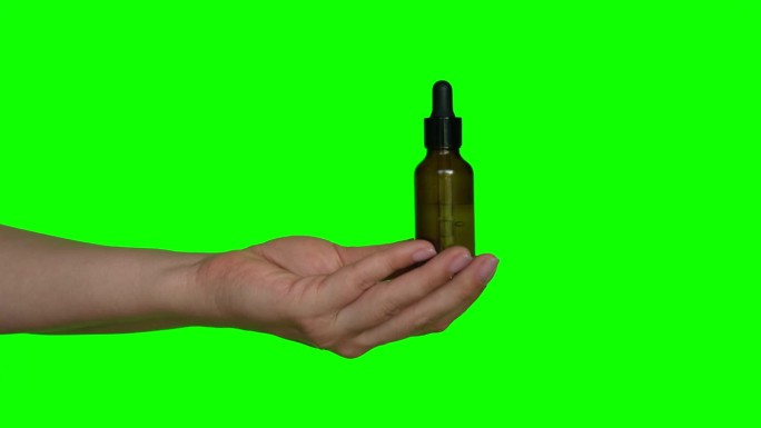 女性的手在色度绿色屏幕背景上测试天然油化妆品。带移液器的滴管玻璃瓶。水疗中心。美容产品。护肤、推荐、