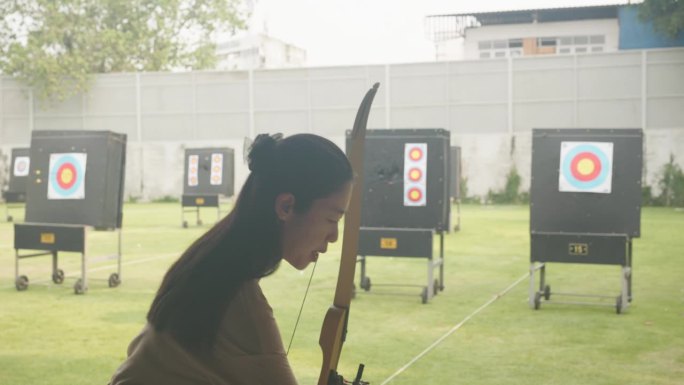 迷人的亚洲女性在靶场练习射箭。射箭。