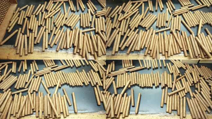 许多手工雪茄卷成一堆，随意地散落在一张木桌上。这家工厂生产世界上最好的雪茄