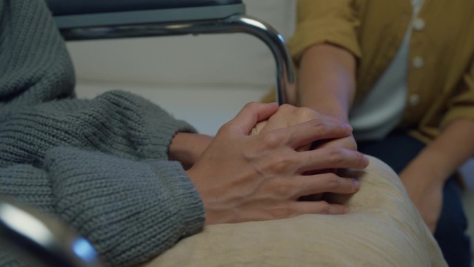 年轻的亚洲人牵手的特写信任安慰帮助癌症患者说话哭泣晚上在家里的客厅减压。医疗保健。